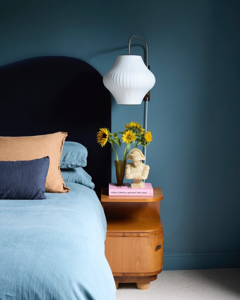 bedroom balances deep navy walls with warm, natural elements