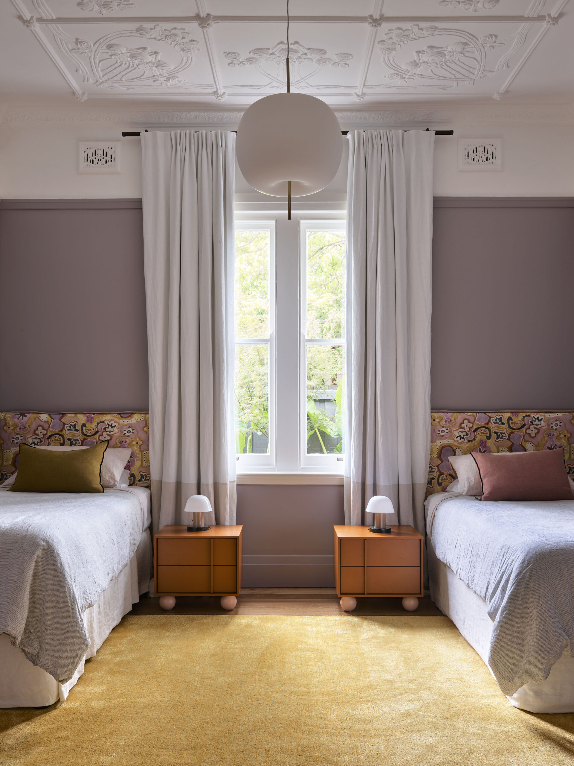 A bedroom with a two single beds, and lavender-painted walls